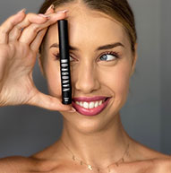 Smiling model covering her eye with a Nanobrow serum bottle