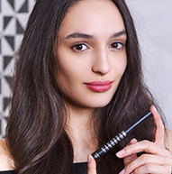 Fair-skinned model holding the Nanobrow shampoo bottle with two fingers