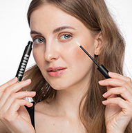 Woman looking at the camera, holding eyebrow serum