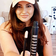 Model in a white cap holding Nanobrow serum bottle and applicator